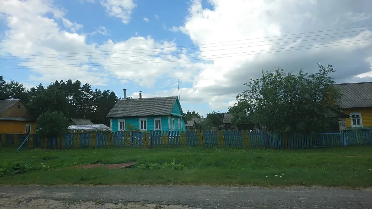 Голубой забор вдоль сельской улицы перед домами
