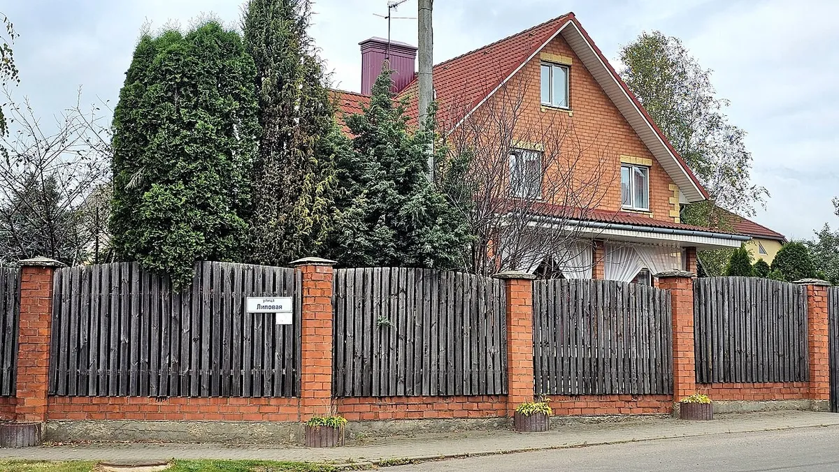 Забор с кирпичными столбами и деревянными секциями перед частным домом